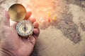 Tourists hold a compass and locate a place on a world map. Royalty Free Stock Photo