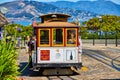 Tourists holding white on trolley streetcar on flat road with San Francisco Bay and mountains