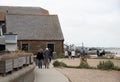 Tourists and locals walk along the seafront pathway seaside with traditional British houses in Whitstable kent England. Royalty Free Stock Photo