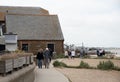 Tourists and locals walk along the seafront pathway seaside with traditional British houses in Whitstable kent England. Royalty Free Stock Photo