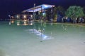 Tourists and locals walk at night along the Cairns city pool - Queensland, Australia