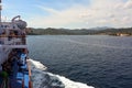 Tourists look from the side of a large sea ship at the coast with sights and landscape