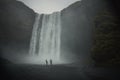 Tourists look at the irresistible beauty of the waterfall on a foggy day Royalty Free Stock Photo