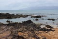 Tourists looking in tide pools on a rocky shoreline at Napili Beach in Lahaina, Maui