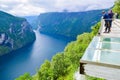 Tourists looks at Geirangerfjord and Seven Sisters Waterfall near small village of Geiranger. View from Eagles Road viewpoint Royalty Free Stock Photo