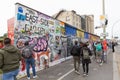 Tourists making photos of the art paintings on the ruins from Berlin Wall