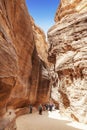 Tourists in narrow passage of rocks of Petra canyon in Jordan. Petra has been a UNESCO World Heritage Site since 1985.