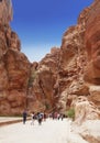 Tourists in narrow passage of rocks of Siq canyon in Jordan. Way through Siq gorge to stone city Petra. Royalty Free Stock Photo