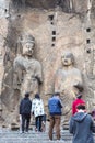 Tourists near Buddhist sculptures in grotto