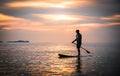 Tourists paddle surfboards in the sunset on a day when the sea has little waves