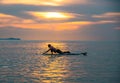 Tourists paddle surfboards in the sunset on a day when the sea has little waves