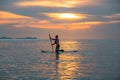 Tourists paddle surfboards in the sunset on a day when the sea has little waves