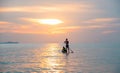 Tourists paddle surfboards in the sunset on a day when the sea has little waves