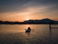 Tourists paddling in canoe on the lake and sunset over mountain Royalty Free Stock Photo