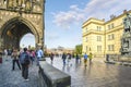 Tourists pass by the statue of Charles IV and Bridge Museum through the Old Town tower with St. Vitus Cathedral in view in Prague Royalty Free Stock Photo