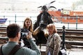 Tourists photograph themselves together with famous statue