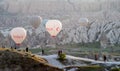 Tourists are photographed against the background of flying balloons in the vicinity of the Goreme