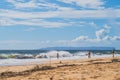 Tourists play in the large crashing surf of pacific ocean in Hawaii