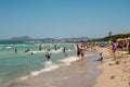 Tourists in Playa de Muro beach with Can Picafort town and mountain in background