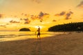 Tourists playing frisbee on the beach in golden sunset