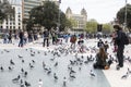 Tourists in Plaza Catalunya in Barcelona feeding the pigeons and taking pictures of them