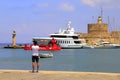 Tourists in port Rhodes take pictures of red submarine, yachts and medieval fortress. Summer vacation at the sea, beautiful place