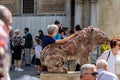 Tourists posing with one of the red marble lions in the Piazzetta dei Leoncini, by St Mark`s Square