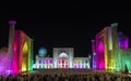 Tourists on Registan Square in Samarkand with Ulugbek Madrasah, Sherdor Madrasah and Tilla-Kari Madrasah at night during a color s Royalty Free Stock Photo