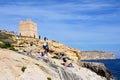 Tourists relaxing by Blue Grotto watchtower, Malta.