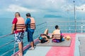 Tourists relaxing on boat deck and looking to the beautiful tropical island