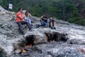 Tourists rest next to natural small fires on Mount Chimaera Yanartas, Turkey