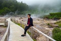 Tourists rest and watching the steam from Hot springs and fumaroles at the edge of lagoa das Furnas, Azores