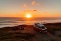 Tourists are resting on the coast of the sea in the rays of sunset with a minivan. Generative ai