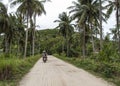 Tourists ridding a scooter on a country road, Thailand