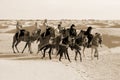 Tourists ride on camels guided by local people on horses