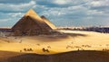 Tourists ride camels on the hills of Giza Plateau near the Great Pyramids Royalty Free Stock Photo
