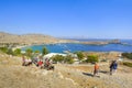 Tourists ride donkeys up the hill towards the Lindos Acropolis with the Bay of Lindos in view on the island of Rhodes, Greece Royalty Free Stock Photo