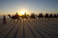 Tourists ride a team of camels along a beach in Australia.
