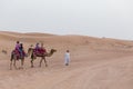 Tourists Riding Camel with Tamer in The Desert of Dubai