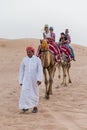 Tourists Riding Camel with Tamer in The Desert of Dubai