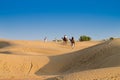 Tourists riding camels, Camelus dromedarius, at sand dunes of Thar desert. Camel riding is a favourite activity amongst all Royalty Free Stock Photo