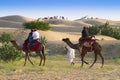 Tourists riding camels, Camelus dromedarius, at sand dunes of Thar desert. Camel riding is a favourite activity amongst all Royalty Free Stock Photo