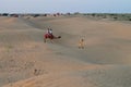 Tourists riding camels, Camelus dromedarius, at sand dunes of Thar desert, Rajasthan, India. Camel riding is a favourite activity Royalty Free Stock Photo