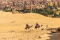 Tourists riding camels on Giza plateau against cityscape of Cairo Royalty Free Stock Photo