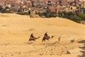 Tourists riding camels on Giza plateau against cityscape of Cairo Royalty Free Stock Photo