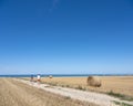 Rolls of straw on field under blue sky with ocean in the background in french normandy Royalty Free Stock Photo