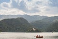 Tourists on a rowing boat in front of Blejsko ostrvo, bled island, on Bled lake or Blejsko Jezero, with assumption of Maria church