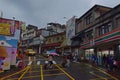 Tourists rushing to cross the road pulling luggage with umbrellas on a rainy day in Jiufen modern town Royalty Free Stock Photo