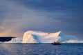 Tourists or scientists at sea with icebergs at sunset at polar night