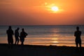 Tourists at sea on the beach, admire the sunrise. Silhouettes of people